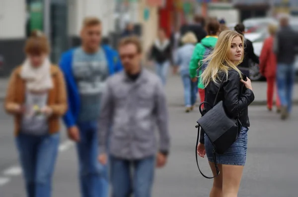 Chica rubia bonita en multitud al aire libre. La chica miró hacia atrás — Foto de Stock