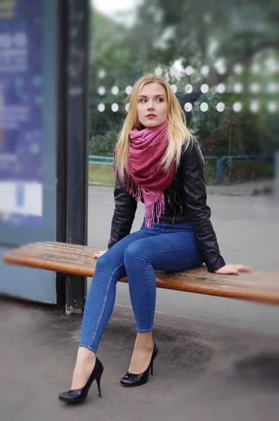 Krásná blond dívka sedí na zastávce MHD — Stock fotografie