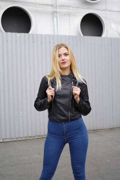 Kvinna i en svart jacka och jeans poserar i staden — Stockfoto