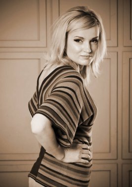 Güzel bir kızın stüdyo portresi. O çizgili örgü bluz ve beyaz kot giymiş. 1970'lerin tarzında giyim.