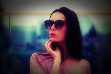 İçinde büyük güneş gözlüğü poz uzun saçlı Genç esmer kadın. Pembe tonları ile moda stil. Arka plan bulanık.