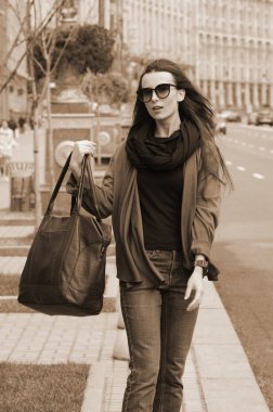 Çanta güneş gözlüğü ile şehirde siyah saçlı bir kadın