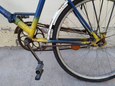 Eski bir bisiklet parçası sarı boyalı, mavi
