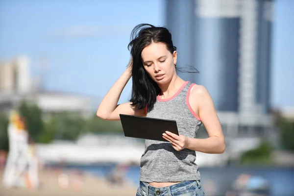 Młoda kobieta za pomocą cyfrowego tabletu w parku — Zdjęcie stockowe
