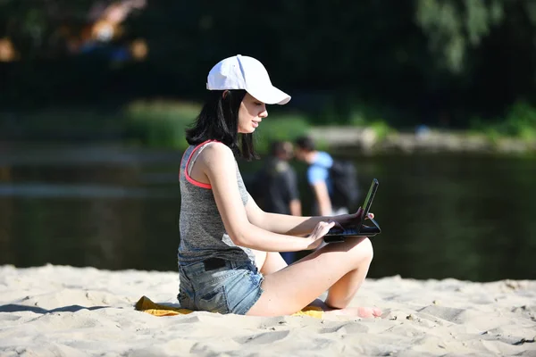 Młoda kobieta pracuje z tabletem na plaży — Zdjęcie stockowe