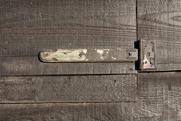 Fechar de uma dobradiça velha em uma porta de madeira — Fotografia de Stock