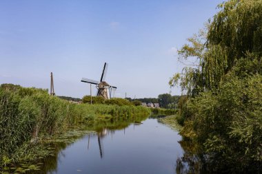 Yel değirmeni çiftlik nehir manzarası. Yel değirmeni çiftlik sahnesi. Köy rüzgarı