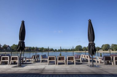 Plaj sandalyesi ve yerde tropi ile kahverengi ve beyaz şemsiye