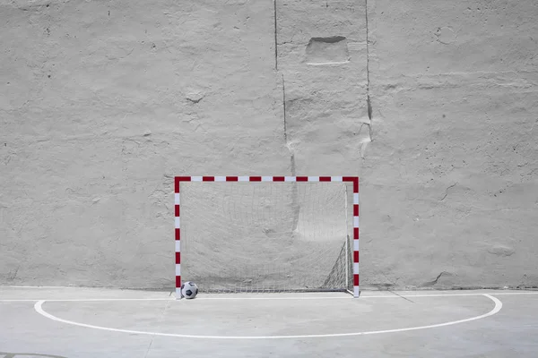 Balón de fútbol y portería con red contra pared enyesada amarilla — Foto de Stock