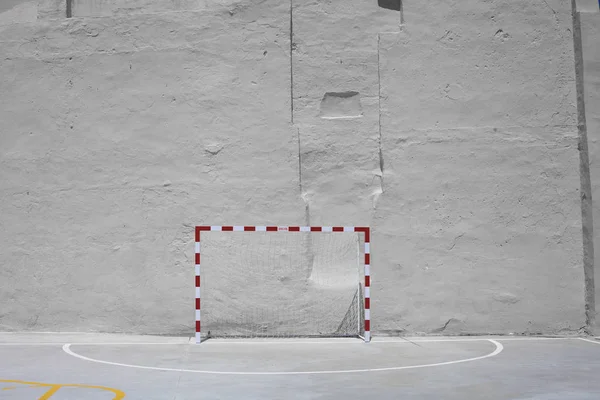 Balón de fútbol y portería con red contra pared enyesada amarilla — Foto de Stock