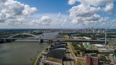 Rotterdam 'daki Van Brienenoord Köprüsü, Nieuwe Maas nehrinin üzerinde doğu yakasındaki kuzey kıyısından görüldü. A16 otoyolunun bir parçası olan iki kemer köprü, sırasıyla 1965 ve 1990 yılında tamamlandı..