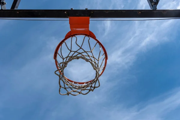 雲一つない暖かい夏の空に対して赤いリングを持つバスケットボールのフープの低い角度からの写真 — ストック写真