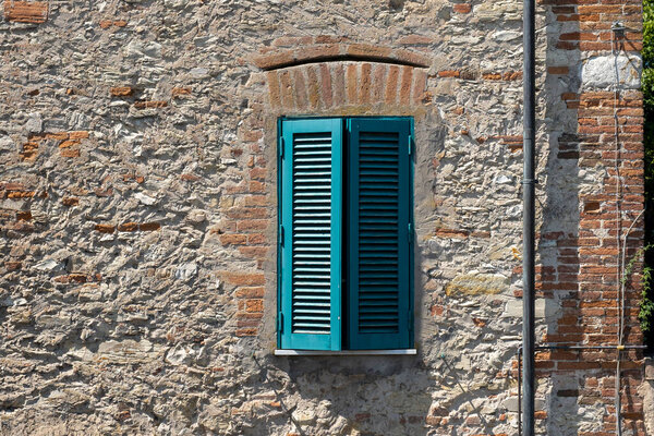 Italian Window with Wooden Shutters in a brick wall. Decorated With Fresh Flowers