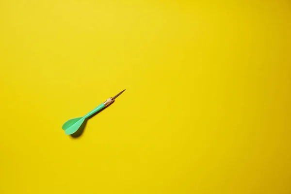 Single green arrow dart isolated on yellow background