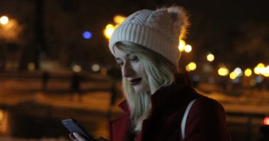 Güzel genç kadın geceleri sokak cep telefonu kullanarak açık portresi. Kış, neşeli Noel arka plan üzerinde Fuarı.