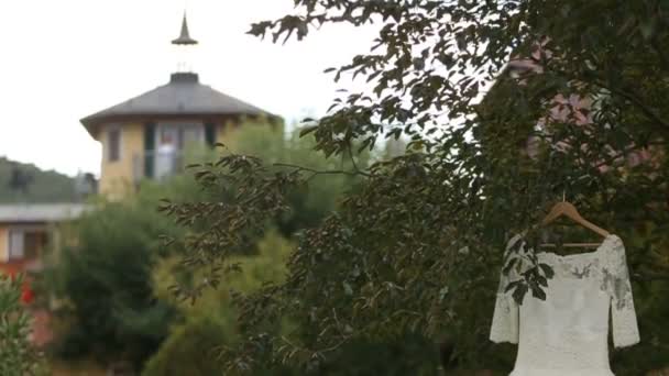 Primer plano de vestido de novia perfecto colgando en el árbol. Mañana nupcial — Vídeos de Stock