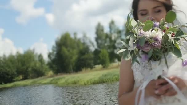 Portret panny młodej w sukni ślubnej z bukietem kwiatów w parku. — Wideo stockowe