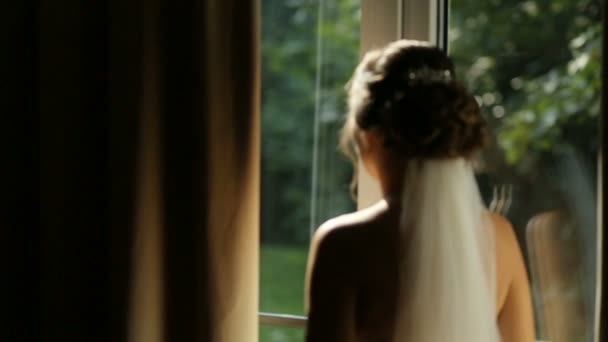 Великолепная невеста в элегантном халате в роскошном гостиничном номере, утром перед подготовкой к свадьбе, отражение в окне — стоковое видео
