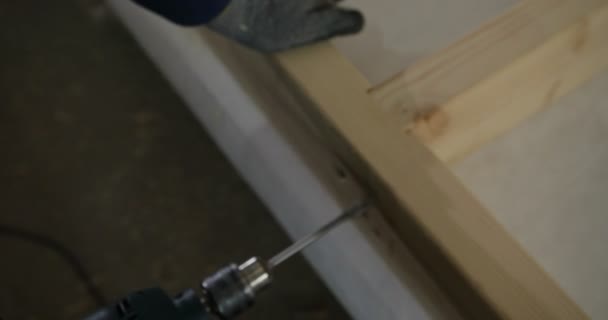 Ξυλουργός τρυπάνι μια τρύπα με ένα ηλεκτρικό τρυπάνι. Ο άνθρωπος διάτρησης σε ξύλο με Δράπανο μπαταρίας — Αρχείο Βίντεο