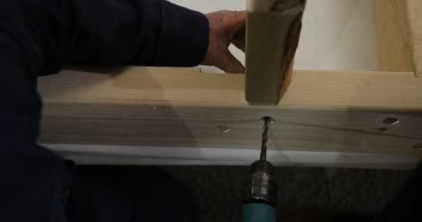 Carpinteiro faz um buraco com uma broca elétrica. Trabalhos em madeira de empreiteiro com ferramentas de construção . — Vídeo de Stock
