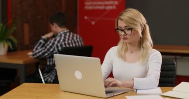 Ofiste çalışan şık sarışın kadın. Onu laptop kullanarak Internet haber okuma sayfa, kaydırma beyaz bir kız. Ekip çalışması insanlar kavramı