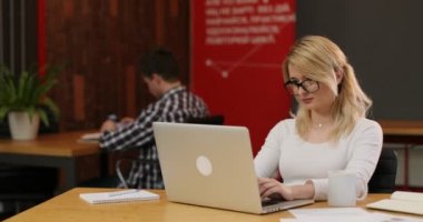 Ofiste çalışan şık sarışın kadın. Onu laptop kullanarak Internet haber okuma sayfa, kaydırma beyaz bir kız. Ekip çalışması insanlar kavramı