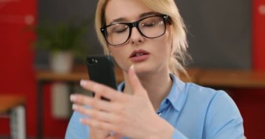 Yakın çekim bir kadeh bardaklarda akıllı telefon kullanma office çekici kadın. Ofiste, kapalı telefonda konuşurken iş kadın hücresi kapatın. Atış kapatın. Portre vurdu