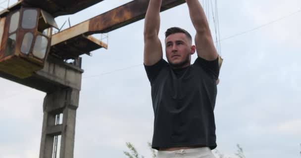 Hombre deportista haciendo ejercicios, preparándose para el entrenamiento de la mañana al aire libre. Urbano, industrial. Fuerza y motivación.Fitness hombre calentando — Vídeo de stock