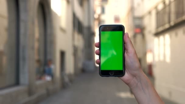 Primer plano de las manos del hombre sosteniendo el teléfono inteligente con pantalla verde en el fondo srteet ciudad. Clave de croma . — Vídeo de stock