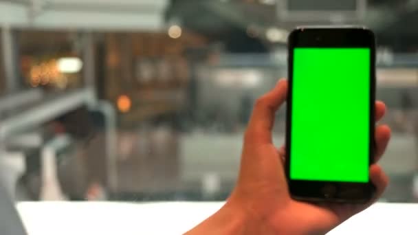 Close up shot of man hands holding the cell phone with green screen on escalators at stylish modern shopping center background. Chroma key. — Stock Video