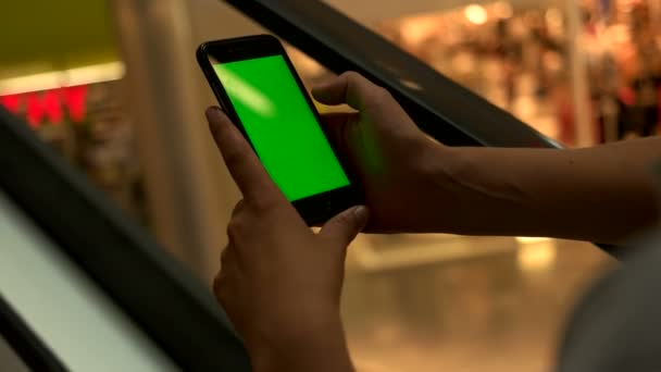 Homem jovem usando telefone inteligente com tela verde enquanto faz as compras no centro comercial à noite. Chave Chroma . — Vídeo de Stock