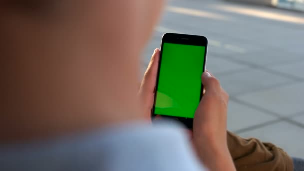 手持和触摸绿色屏幕的智能手机在机场的男子手。关门了色度键. — 图库视频影像