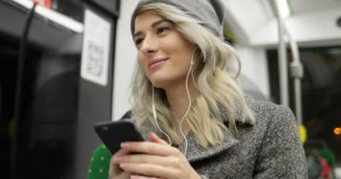 Müzik üstünde hareket eden telefon içinde toplu taşıma gülümseyen şirin kız portresi. Şehir ışıkları arka plan