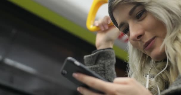 검색 및 대 중 교통으로 여행 하는 동안 그녀의 전화에 메시지를 입력 웃는 귀여운 여자의 초상화. 도시 — 비디오