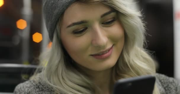 Ritratto di una ragazza carina sorridente che naviga e digita un messaggio sul suo telefono mentre viaggia sui mezzi pubblici. Urbano — Video Stock