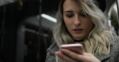 Tarama ve toplu taşıma araçları üzerinde seyahat ederken ona telefon mesaj yazarak gülümseyen bir sevimli kız siyah şapkalı yakın çekim portresi. Şehir ışıkları arka plan