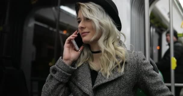 Alguien llamando. Chica joven en sombrero negro respondiendo a la llamada en un transporte público — Vídeo de stock