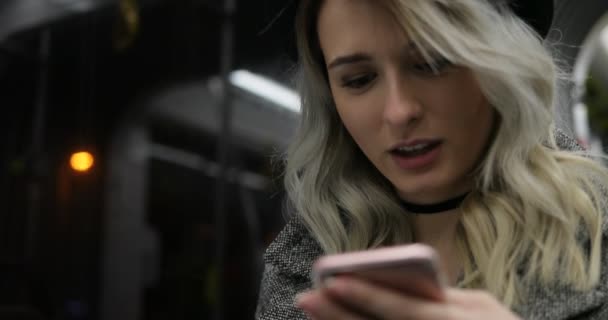 Close-up portret van een lachende schattig meisje in zwarte hoed, surfen en te typen bericht op haar telefoon onderweg op het openbaar vervoer. — Stockvideo