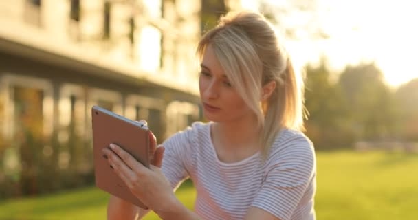 Estudiante joven usando tableta en el parque. Chica haciendo compras en línea en la tableta PC — Vídeos de Stock