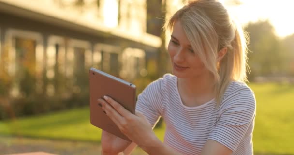 Jovem estudante usando tablet no parque. Menina fazendo compras on-line no tablet pc — Vídeo de Stock