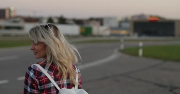 Menina hipster jovem atraente andando pela rua, olhando para a câmera e sorri — Vídeo de Stock