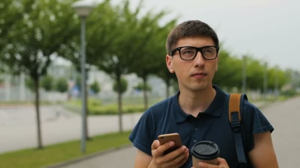 Primo piano colpo di uomo negli occhiali con lo zaino a piedi vicino al terminal dell'aeroporto e utilizzando lo smartphone . — Video Stock