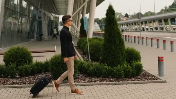 Stijlvolle jonge zakenman met de bagage die lopen naar de luchthaventerminal aan de lounge zone. — Stockvideo