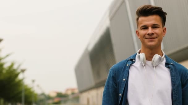 Retrato de homem emocional atraente em camisa jeans girando para a câmera e sorrindo no fundo do aeroporto . — Vídeo de Stock