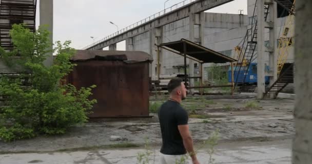 Portret van gezonde jonge sport man wandelen door industriële stadspark en op zoek weg. Zelfverzekerde jonge man klaar van training. — Stockvideo