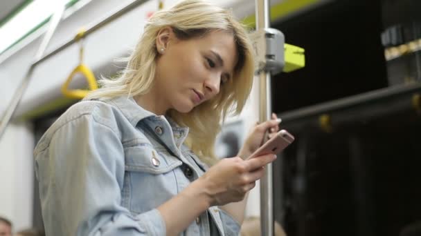 Retrato de chica, sostiene la barandilla, escuchando música y navegando en el teléfono móvil en transporte público. Ciudad luces fondo — Vídeos de Stock