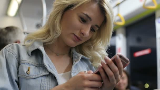 Ritratto di una ragazza carina sorridente che naviga e digita un messaggio sul suo telefono mentre viaggia sui mezzi pubblici . — Video Stock