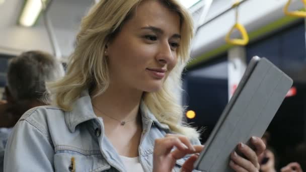 Retrato de linda chica sostiene la tableta PC, la navegación en el ordenador portátil en el transporte público. Ciudad luces fondo — Vídeos de Stock