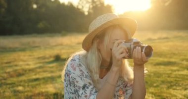 Neşeli genç sarışın kadının yaz sunset Bulvarında alanında vintage fotoğraf makinesinde fotoğrafların yakın çekim.