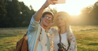 Neşeli genç erkek ve smartphone kamerada güzel selfie fotoğraf çekmek ve alanında güzel doğada öpüşme kız yakın çekim.